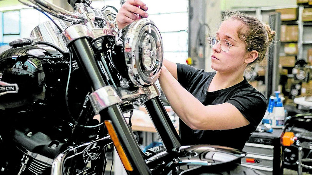 Maja Vukojevic tauscht die Chromblenden an einem Motorrad. 