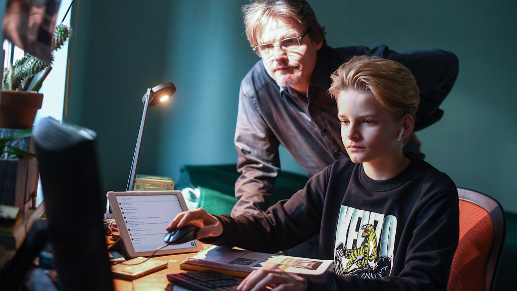 Der Vater sieht seinem Sohn zu, wie der Fernunterricht funktioniert.