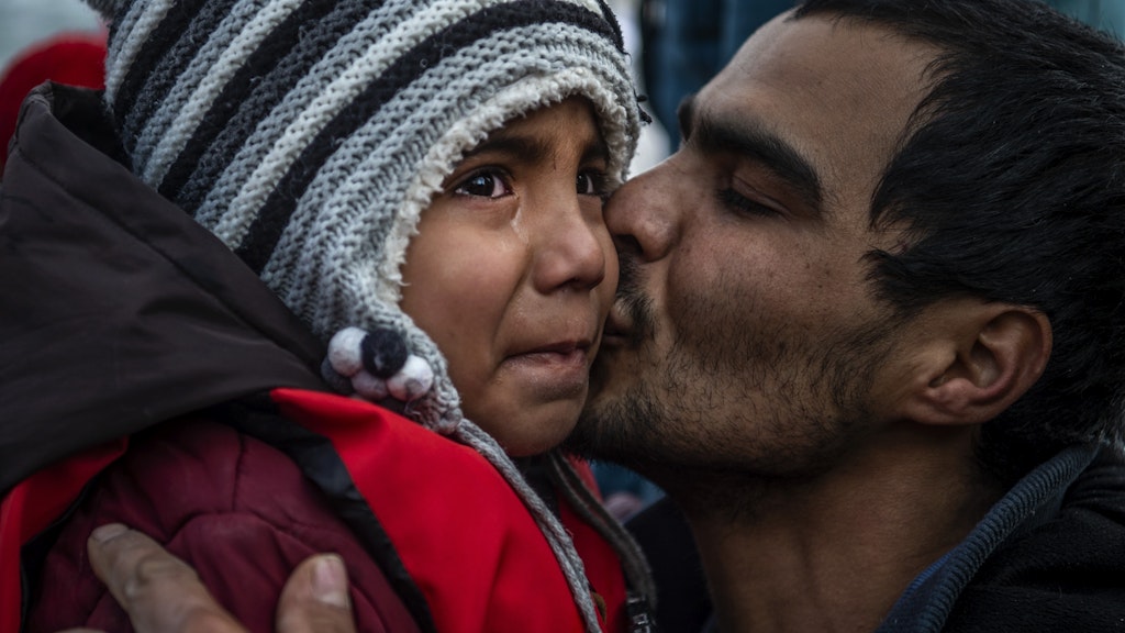 Liebevoll küsst ein Vater sein Kind, nachdem die beiden die Überfahrt zur griechischen Insel Lesbos geschafft haben.