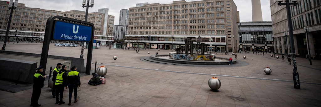 Sicherheitskräfte der Berliner Verkehrsbetriebe (BVG) stehen am Eingang zum U-Bahnhof am Alexanderplatz. Aufgrund der Corona-Krise ist der Zentrale Alexanderplatz im Osten der Hauptstadt weitgehend menschenleer. 