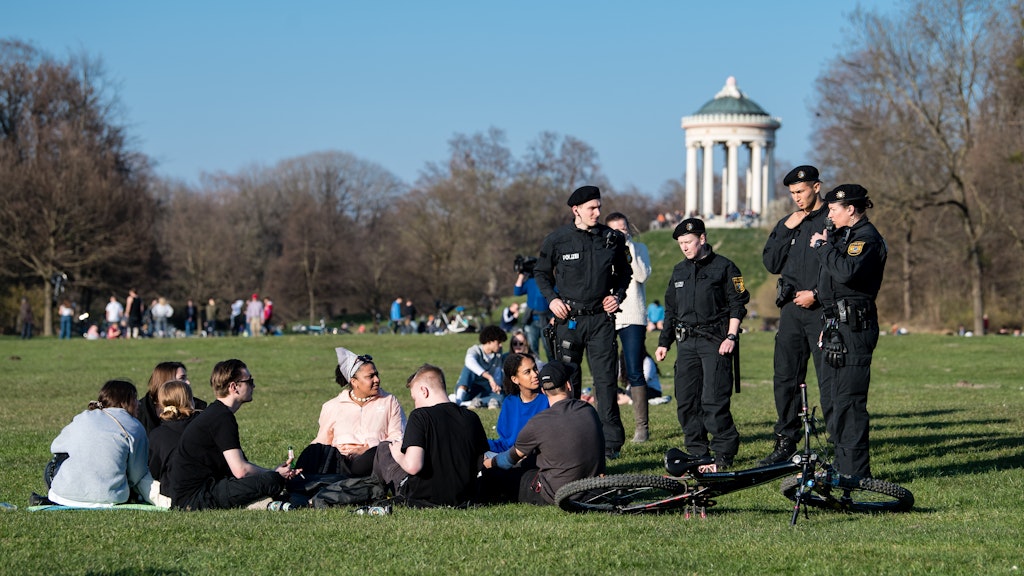 Polizisten reden im Englischen Garten mit einer Gruppe Jugendlicher. Die Münchner Polizei patrouillierte in Parks, um auf die Einhaltung der von der Staatsregierung verordneten Abstandsregelungen zu drängen.