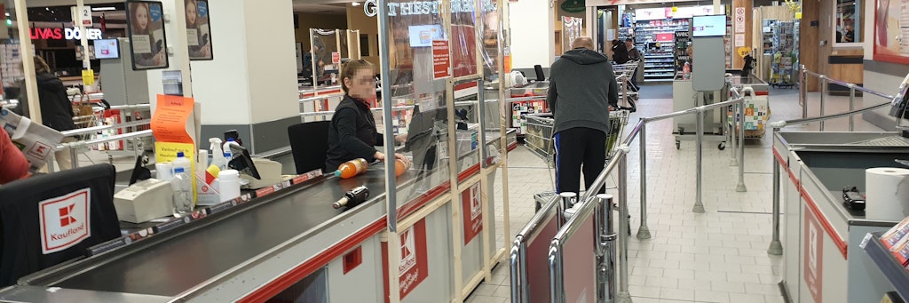 Diese Kassiererin soll durch eine Trennwand vor einer Tröpfcheninfektion geschützt werden. 