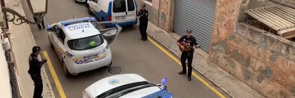 Ein Polizist der spanischen Policia Local auf Mallorca spielt Gitarre, seine Kollegen tanzen und klatschen