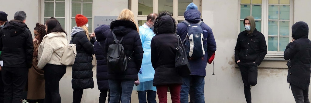 Menschen stehen vor der Corona-Untersuchungsstelle der Charité-Schlange.