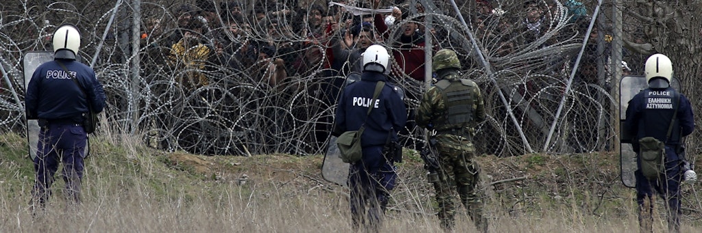 Stacheldraht und Zaun trennen Flüchtlinge und griechische Sicherheitskräfte.