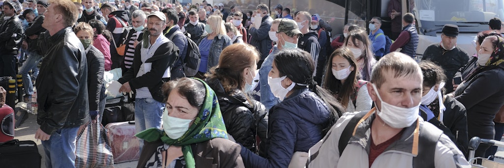 Dicht gedrängt warten Saisonarbeiter mit Mundschutz vor ihrer Abreise nach Deutschland vor dem Flughafen.