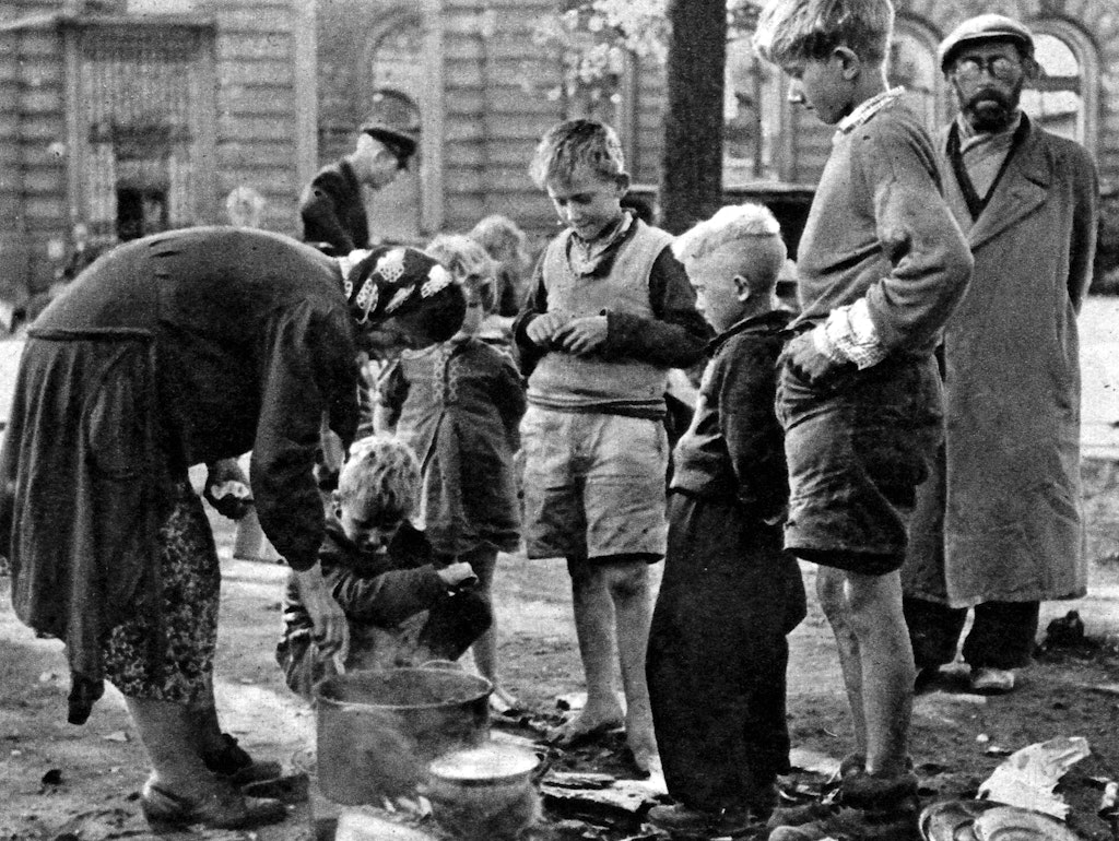 Hunger quält die Menschen im Nachkriegs-Berlin. Diese offensichtlich obdachlose Familie bereitet sich auf einer Straße ein karges Mahl.