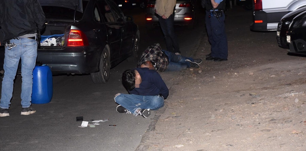 Die beiden aus Rumänien stammenden Raser mit Handschellen nach ihrer Festnahme. Daneben der mit Benzin gefüllte Behälter, den sie im Kofferraum verstaut hatten. 