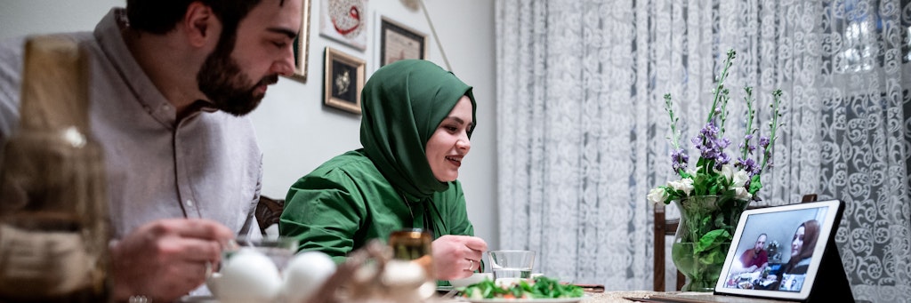 Rabia und Yusuf Simsek sitzen zusammen beim Abendessen und telefonieren mit Freunden. Das junge Paar ist normalerweise an Ramadan fast täglich bei Freunden oder der Familie eingeladen, durch die Corona-Pandemie verbringen beide das Fastenbrechen zu zweit Zuhause. Gesellschaft gibt es nur mittels Videokonferenz.