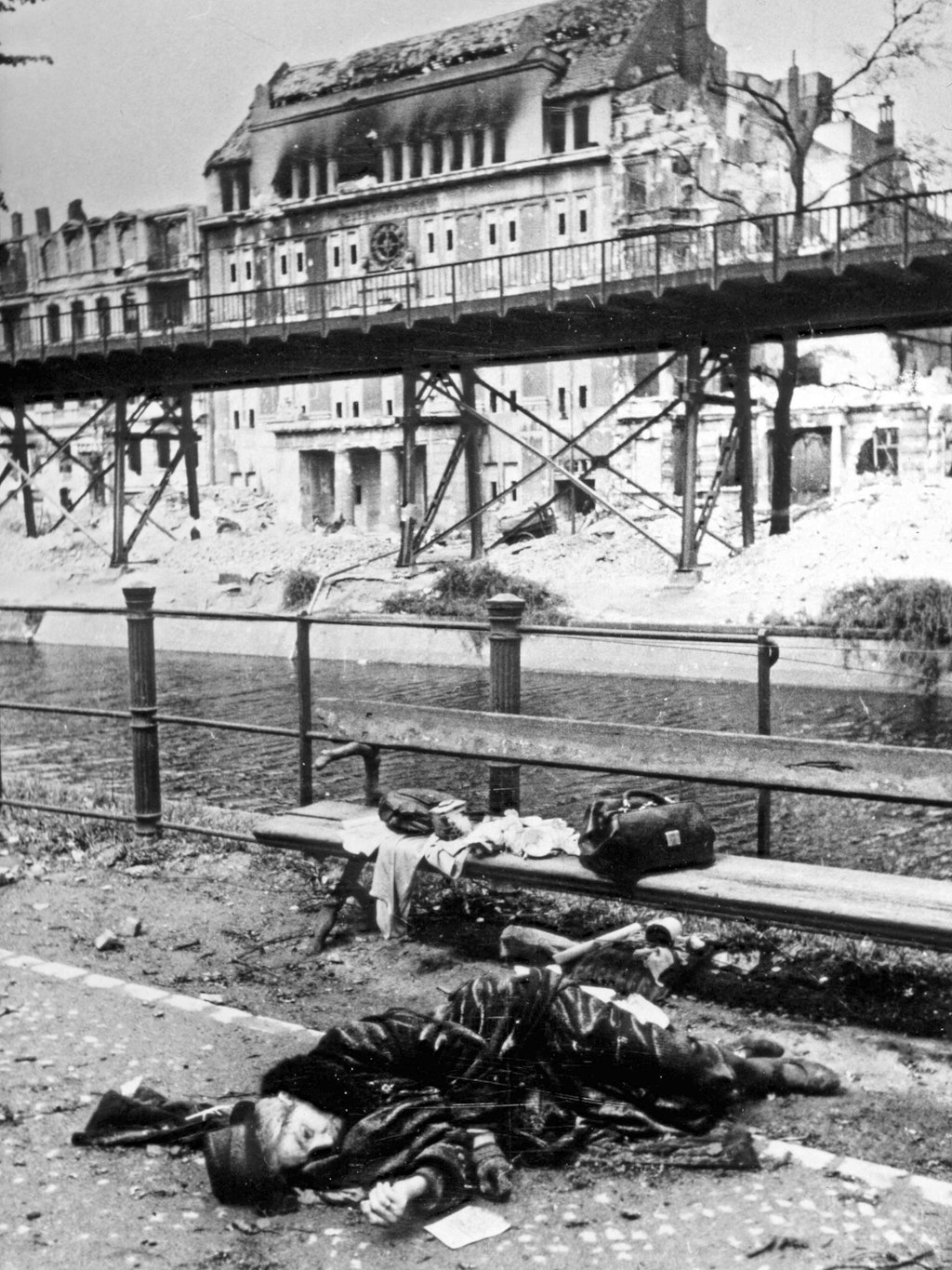 Eine Frau liegt am Halleschen Ufer am Landwehrkanal. Auf der Parkbank befinden sich ihre Habseligkeiten. Sie hat sich, wie nicht wenige Berliner zum Ende des Krieges, umgebracht.
