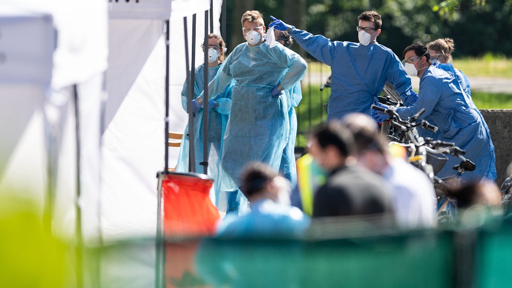 Mitarbeiter vom Gesundheitsamt und dem Deutschem Roten Kreuz warten an den Zelten vor dem Wohnkomplex darauf, Corona-Tests durchzuführen. 