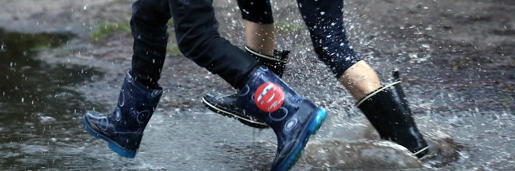Kinder rennen mit Gummistiefeln durch große Regenpfützen. Nach Angaben der Meteorologen wird auch in den kommenden Tagen mit Regenfällen bei sinkenden Temperaturen zu rechnen sein. 