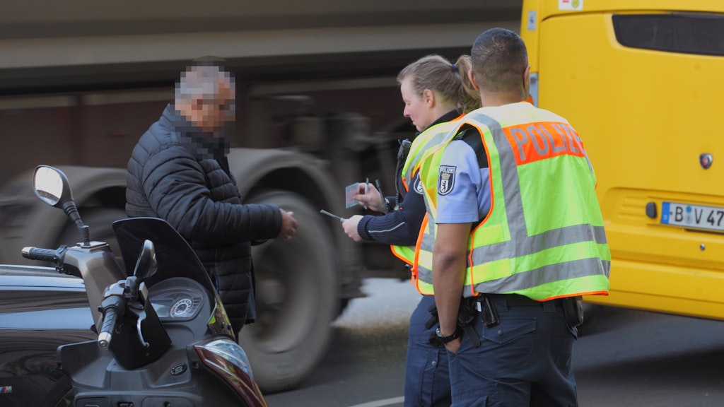 Eine Polizistin ohne Handschuhe überprüft am Hermannplatz in Berlin-Neukölln den Führerschein eines Falschparkers.