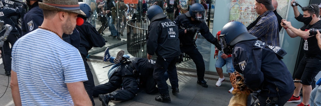 Behelmte Einsatzkräfte der Berliner Polizei sichern eine Festnahme. Dabei kommt auch ein scharfer Polizeihund zum Einsatz.