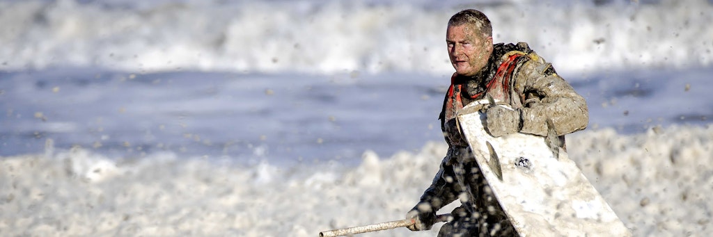 Ein Mitarbeiter der Seenotrettungsorganisation KNRM bergt ein Surfbrett, das die Rettungskräfte bei der erneuten Suche nach den vermissten Wassersportlern im Noordelijk Havenhoofd gefunden haben.