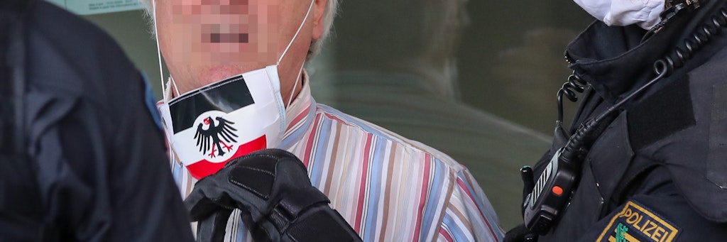 Polizisten nehmen einem Teilnehmer der rechtsextremen Vereinigung Pro Chemnitz einen Mundschutz in den Farben der Reichskriegsflagge und dem Bundesadler ab. Die Reichskriegsflagge ohne Hakenkreuz ist nicht strafbar, wird aber meist von Rechtsextremen verwendet.