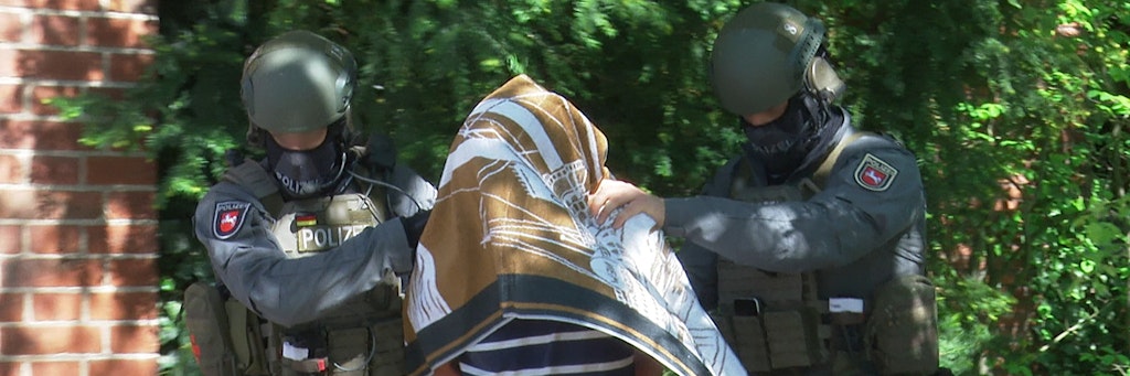 Polizisten führen den Verdächtigen ab. Er soll seinen Tod vorgetäuscht haben.