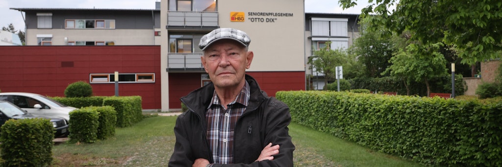 Der 84 Jahre alte Rentner Alfons Blum steht vor dem Seniorenpflegeheim Otto Dix. In diesem Heim wohnt seine Ehefrau, die er seit Beginn der Corona-Einschränkungen nicht mehr sehen kann.