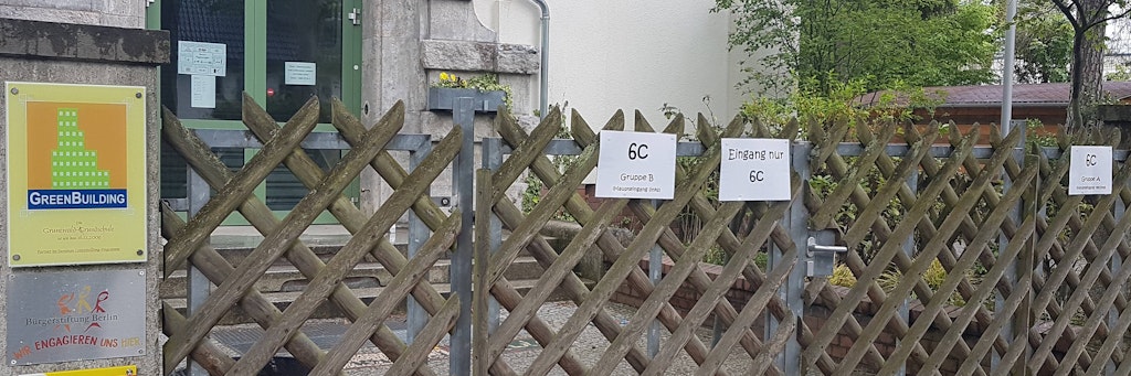 Die Grunewald-Grundschule hat schon mal Hinweisschilder für ihre Schüler an dem Holzzaun Angeklebt, wo sich der Eingang bei Ankunft zum Schulbeginn befindet.