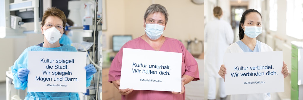 Die Ärzte halten Schilder mit Botschaften, die der Kulturszene den Rücken stärken sollen. In der Mitte: Die leitende Hebamme des Sana-Klinikums, Friederike Knüpling. Ihre Tochter arbeitete im Bereich Regie, ist von der Corona-Krise auch betroffen.