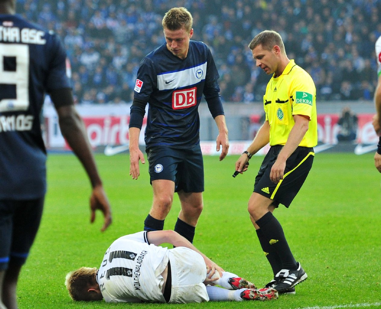 Gladbachs Marco Reus krümmt sich auf dem Rasen vor Schmerzen, weil Maik Franz ihn am Knöchel erwischt hat.