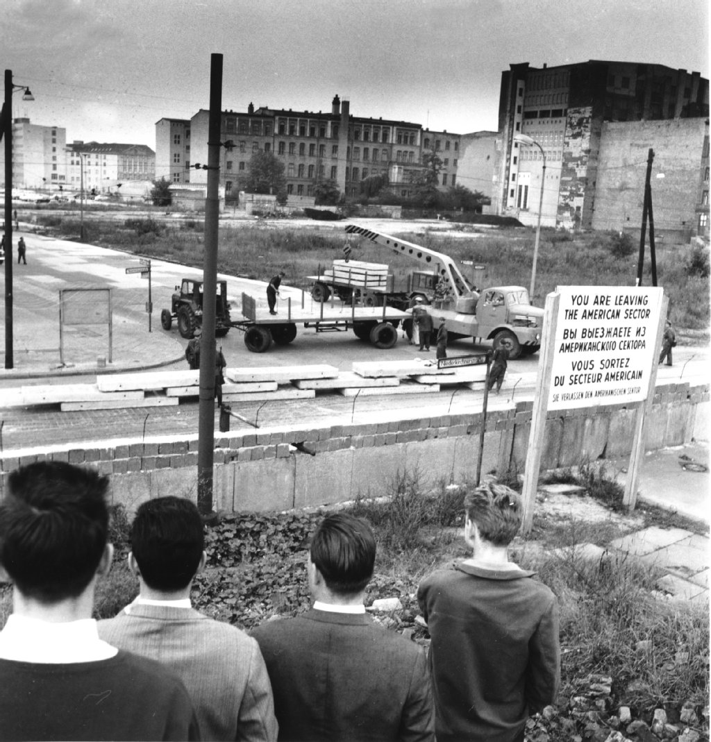 Westberliner schauen an der Wilhelmstrasse in Berlin der Anlieferung vorgefertigter Betonbauteile zur Verstärkung der Berliner Mauer zu.