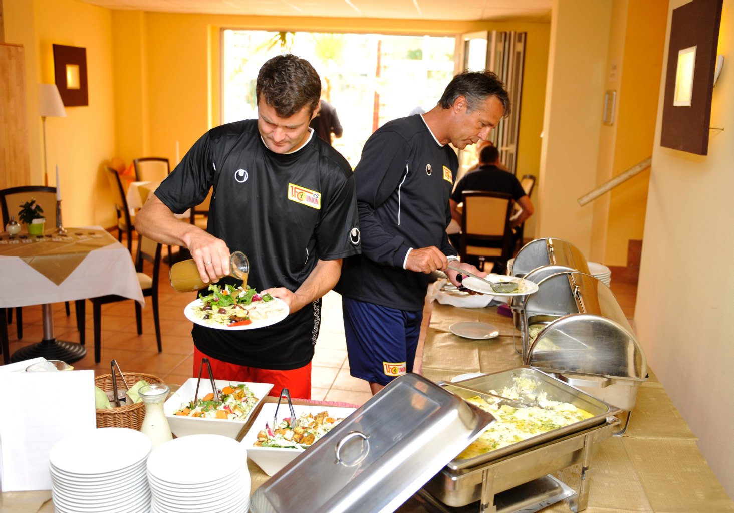 Daniel Göhlert und Trainer Uwe Neuhaus bedienen sich am Buffet.