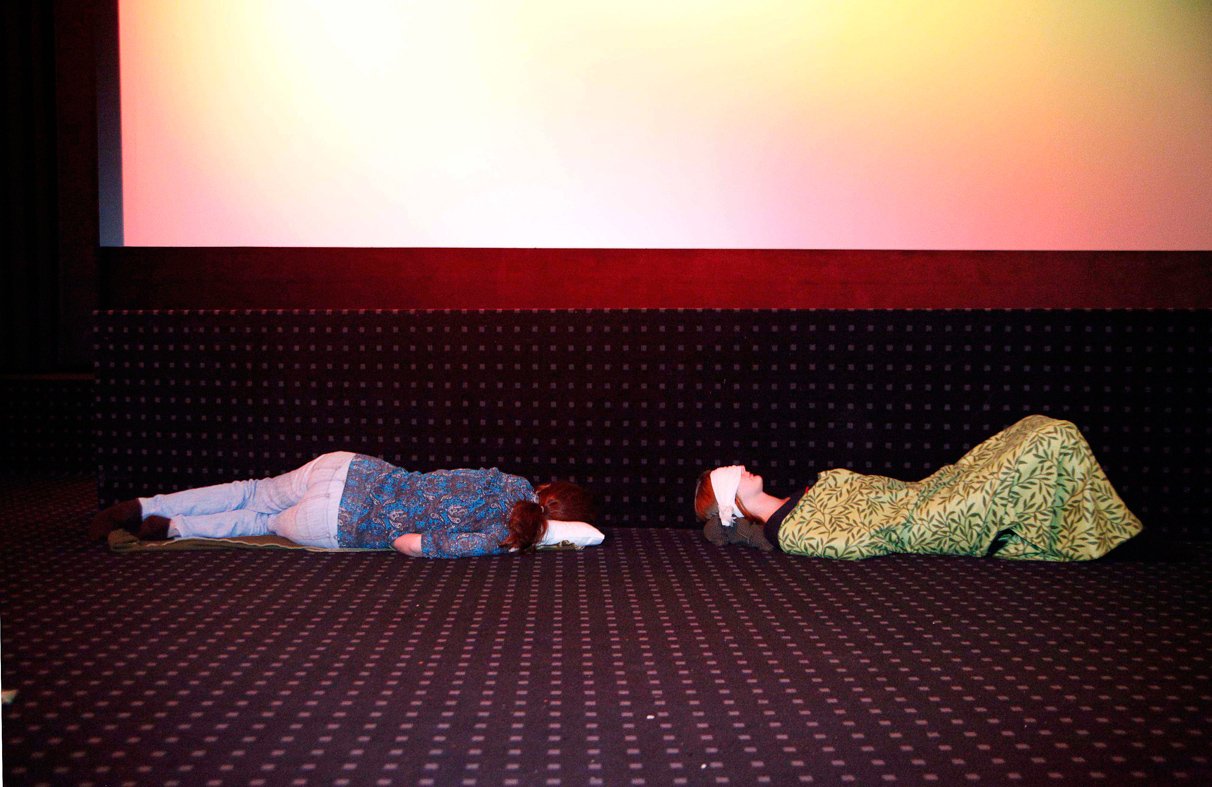 Völlig entkräftete Zuschauer schlummern auf dem Kino-Boden direkt unterhalb der Leinwand.