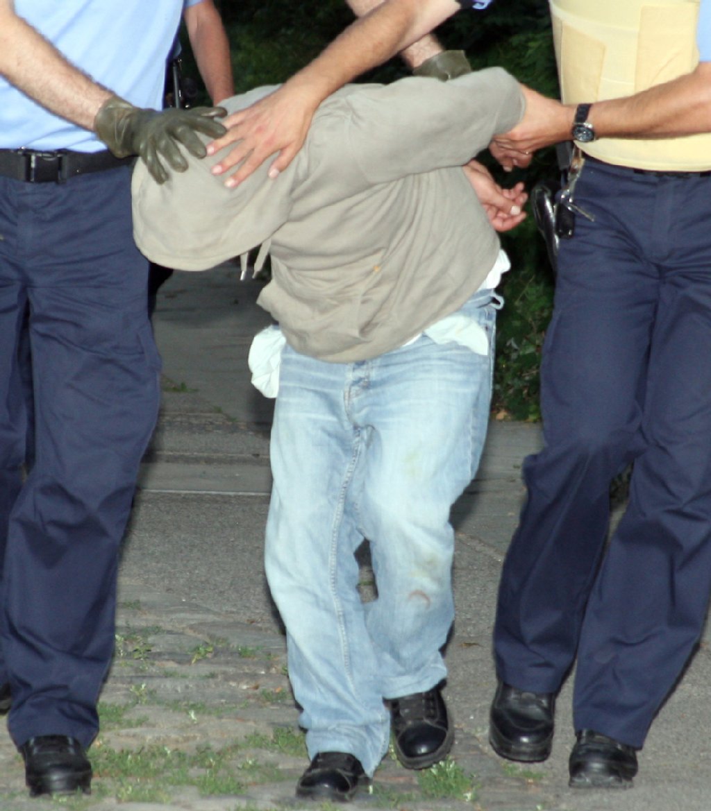 Das Spiel ist aus: Einer der drei Männer wird von Polizisten abgeführt, seine Hände sind mit Handschellen auf den Rücken gefesselt. Kurz zuvor war er mit einer Pistole bewaffnet auf die Beamten losgegangen.