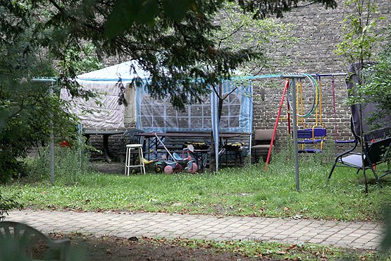 Ein verwilderter Garten, wie für Kinder gemacht, mit Roller und Rutsche.