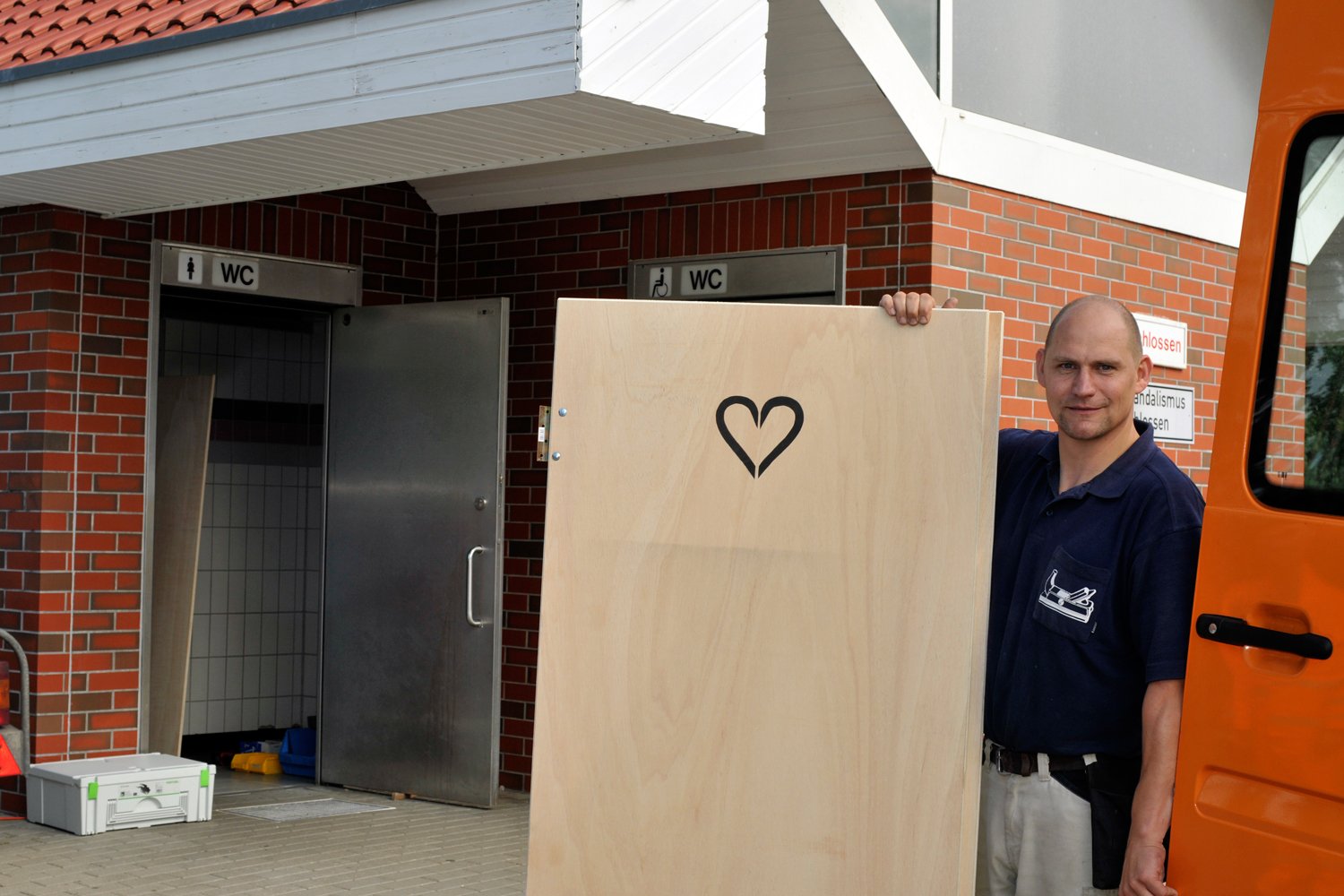 Tischler Dirk Flasche mit einer der Holztüren. Darauf ist das symbolische Herz.