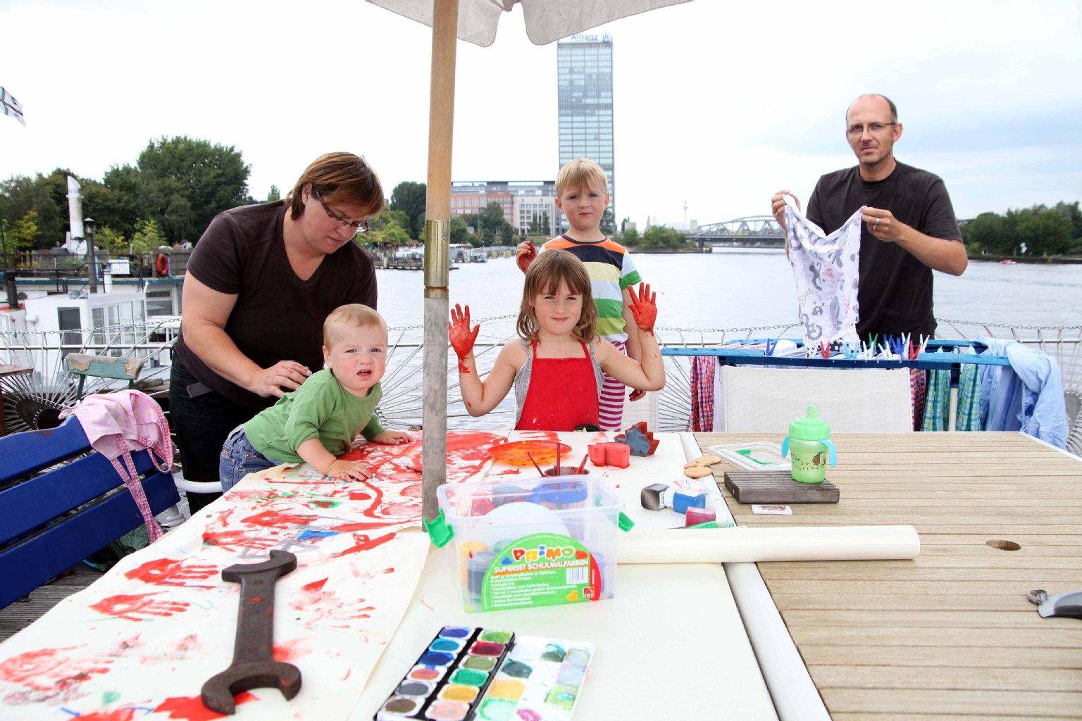 Petra Voerste malt an Deck mit den Kindern, Vater Jochen hängt Wäsche auf.