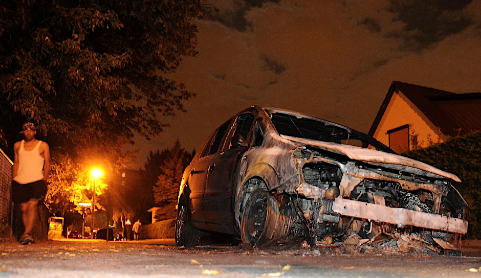 Ein ausgebrannter Opel steht am frühen Morgen in Lichtenberg auf der Straße.
