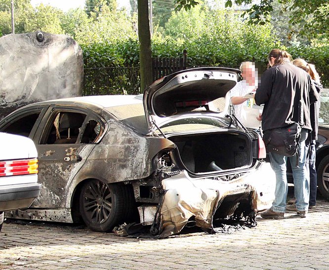 Ermittler untersuchen den ausgebrannten Wagen.
