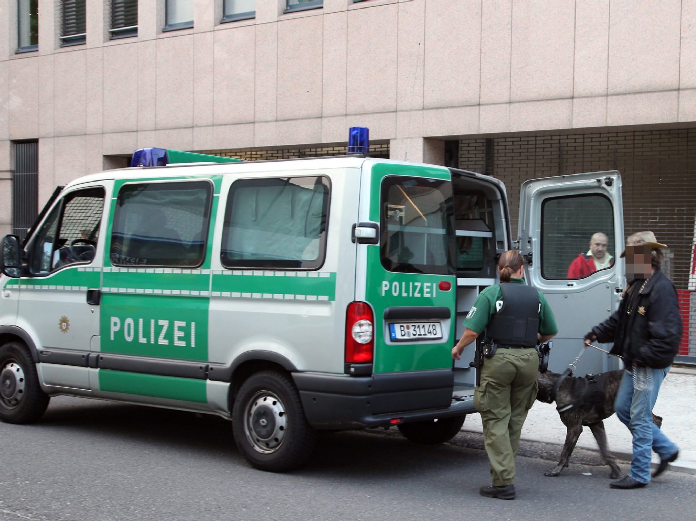 Die Polizei nimmt den Kampfhund mit.