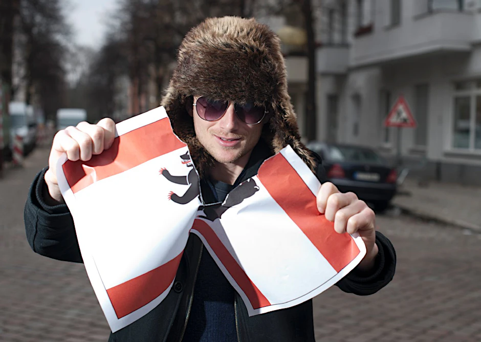 Kristjan Knall zerreißt symbolisch eine Berlin-Flagge. Er gibt offen zu: „Ich hasse diese Stadt und die Menschen.“