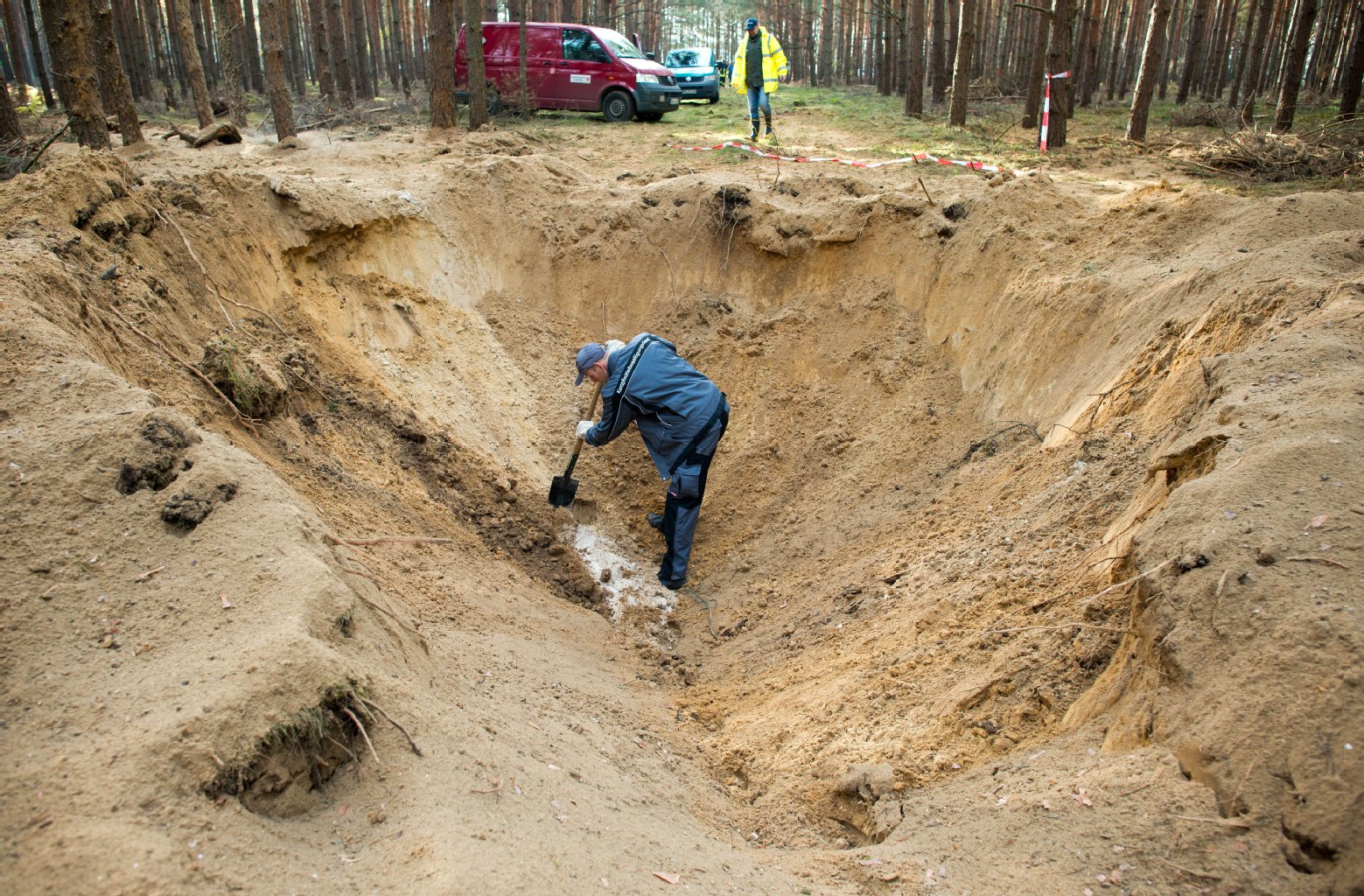 In einem über zwei Meter tiefen und etwa sechs Meter breiten Krater in einem Wald nahe Fürstenwalde steht Matthias Metke vom Kampfmittelbeseitigungsdienst der Polizei.