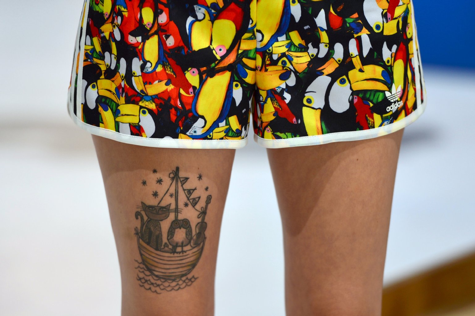 Eine Messehostesse zeigt ihr putziges Katzen-Tattoo an der Wade.