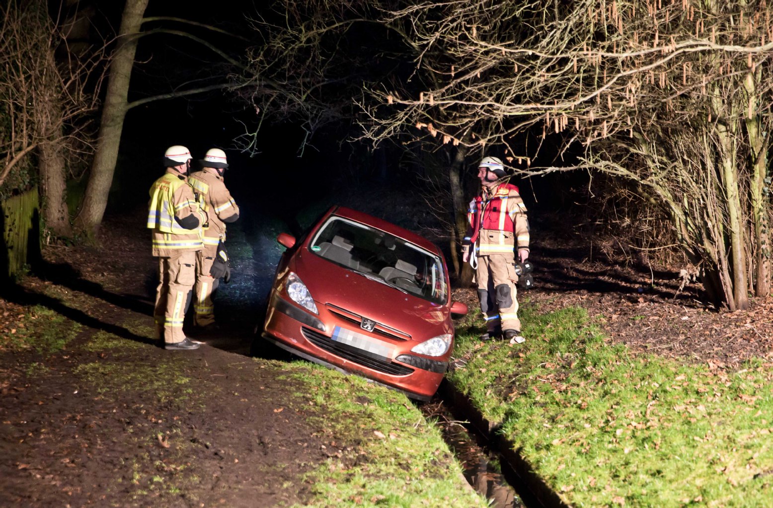 Drei Retter der Feuerwehr stehen bei dem unfreiwillig gewasserten Fahrzeug.