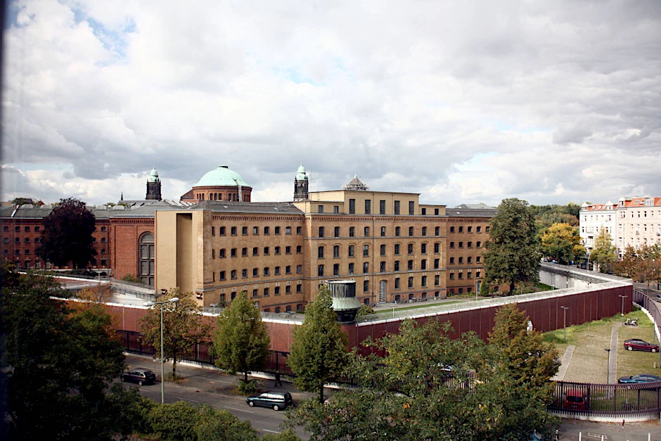 Die Justizvollzugsanstalt Moabit mit der Backsteinmauer und dem Stahlzaun davor.
