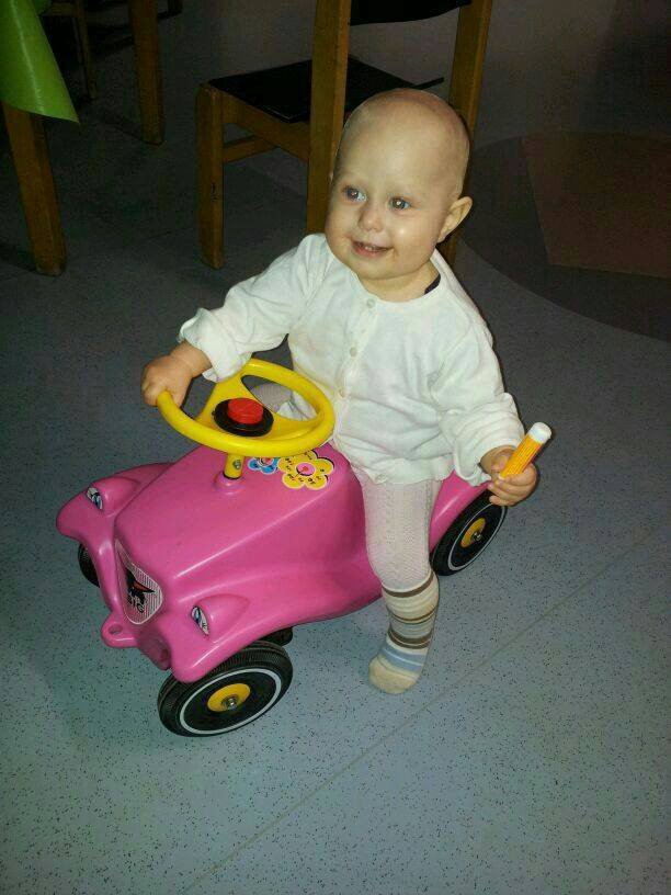 Neele auf ihrem rosafarbenen Bobbycar im Krankenhauszimmer des Virchow-Klinikums.