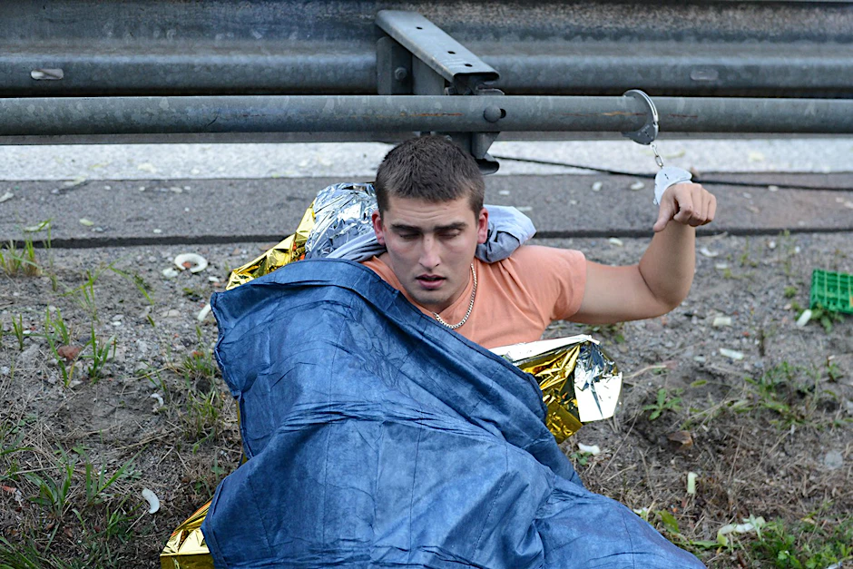 Angekettet an die Leitplanke wartet der gestoppte Dieb auf seinen Weitertransport.