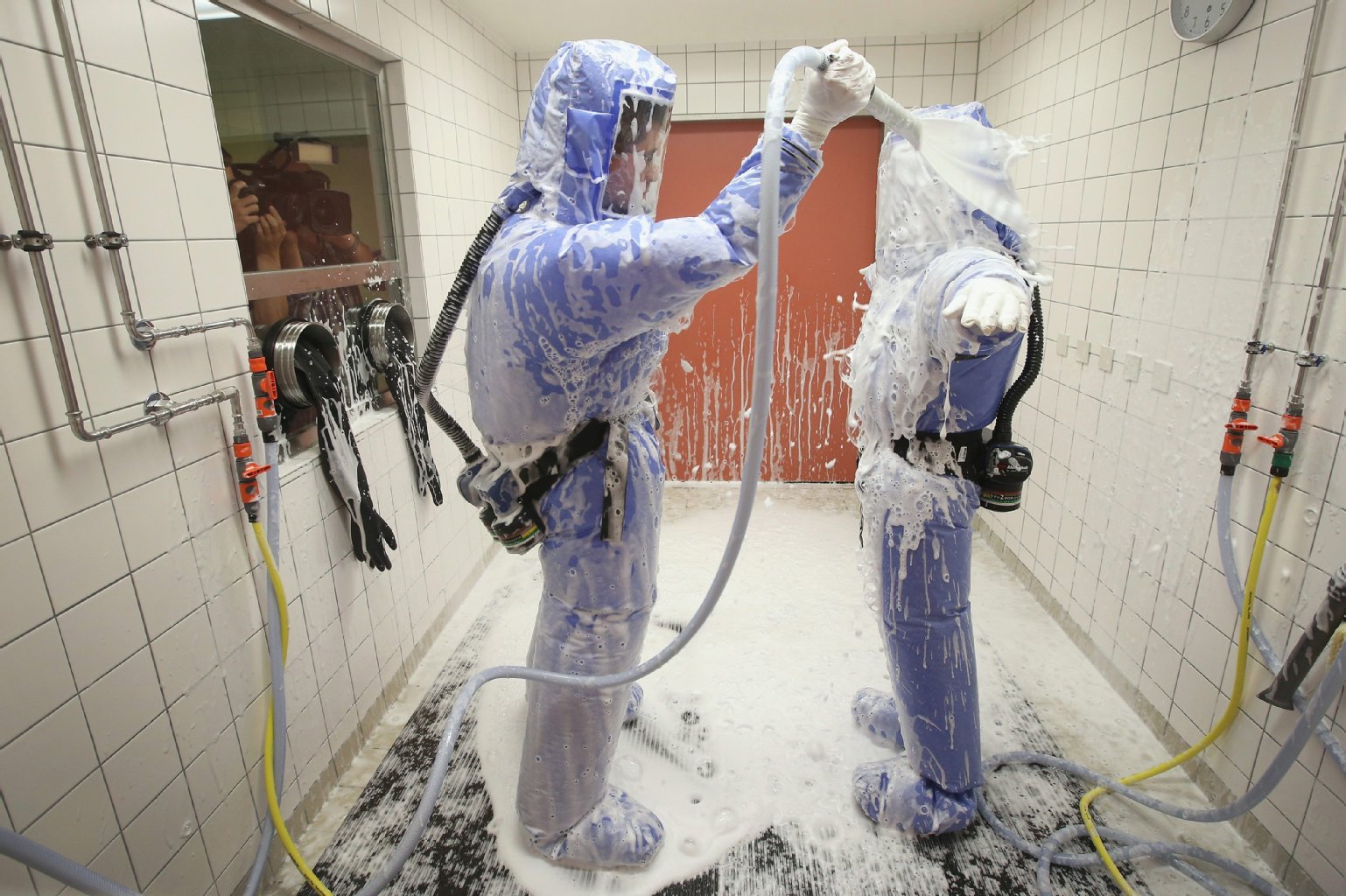 Stationsleiter Thomas Klotzkowski und Tropenmediziner Florian Steiner (r.) bei der Desinfektions-Dusche. Sie atmen gefilterte Luft.
