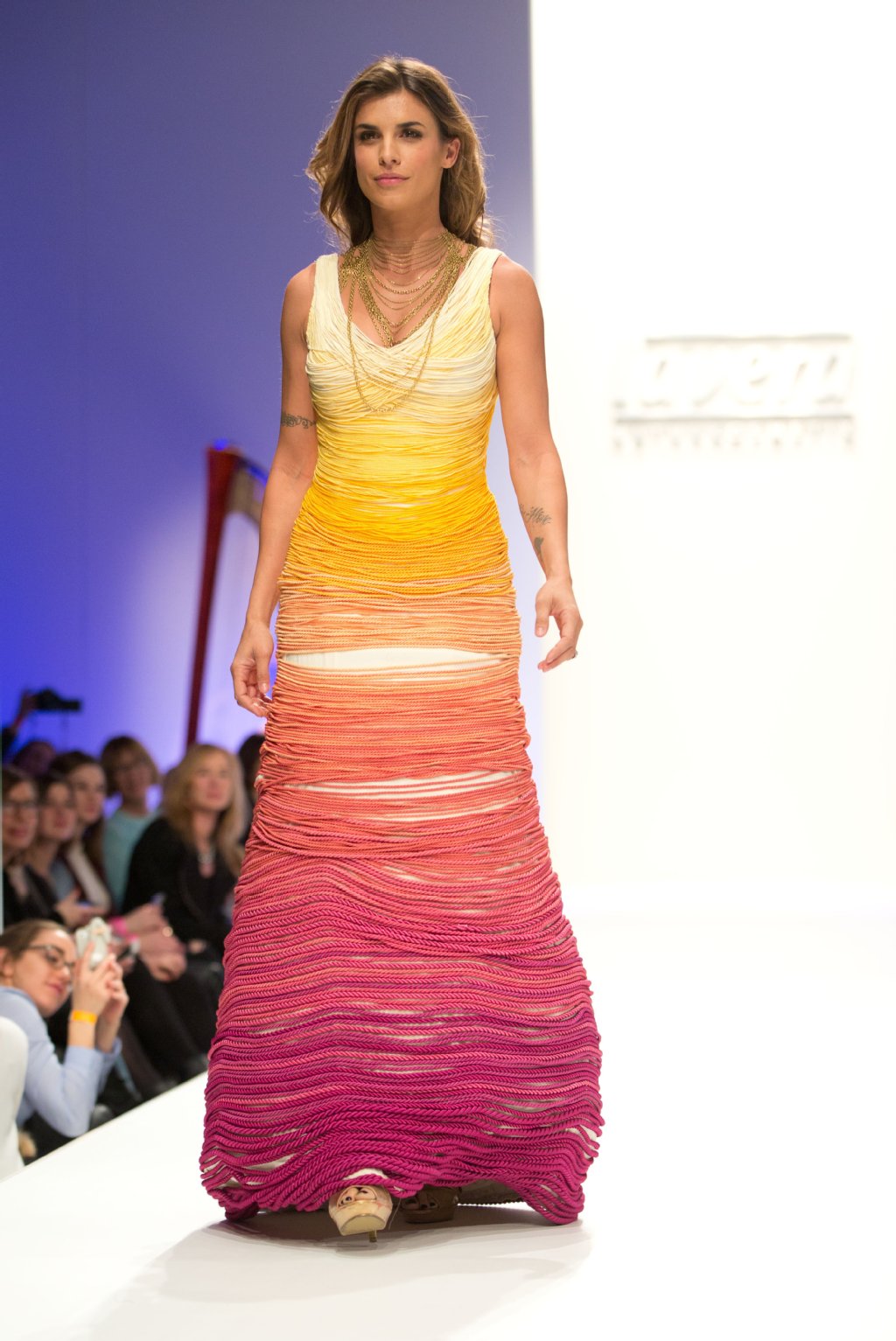 Flop Lavera Showfloor: George Clooneys Ex Elisabetta Canalis trägt den kordeligen Mode-Albtraum einer Nachwuchsdesignerin mit einem Lächeln.