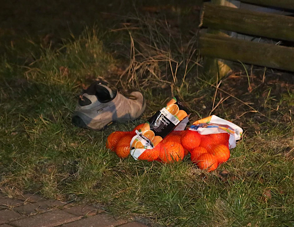 Zwei Netze Orangen und ein Schuh liegen am Wegesrand.
