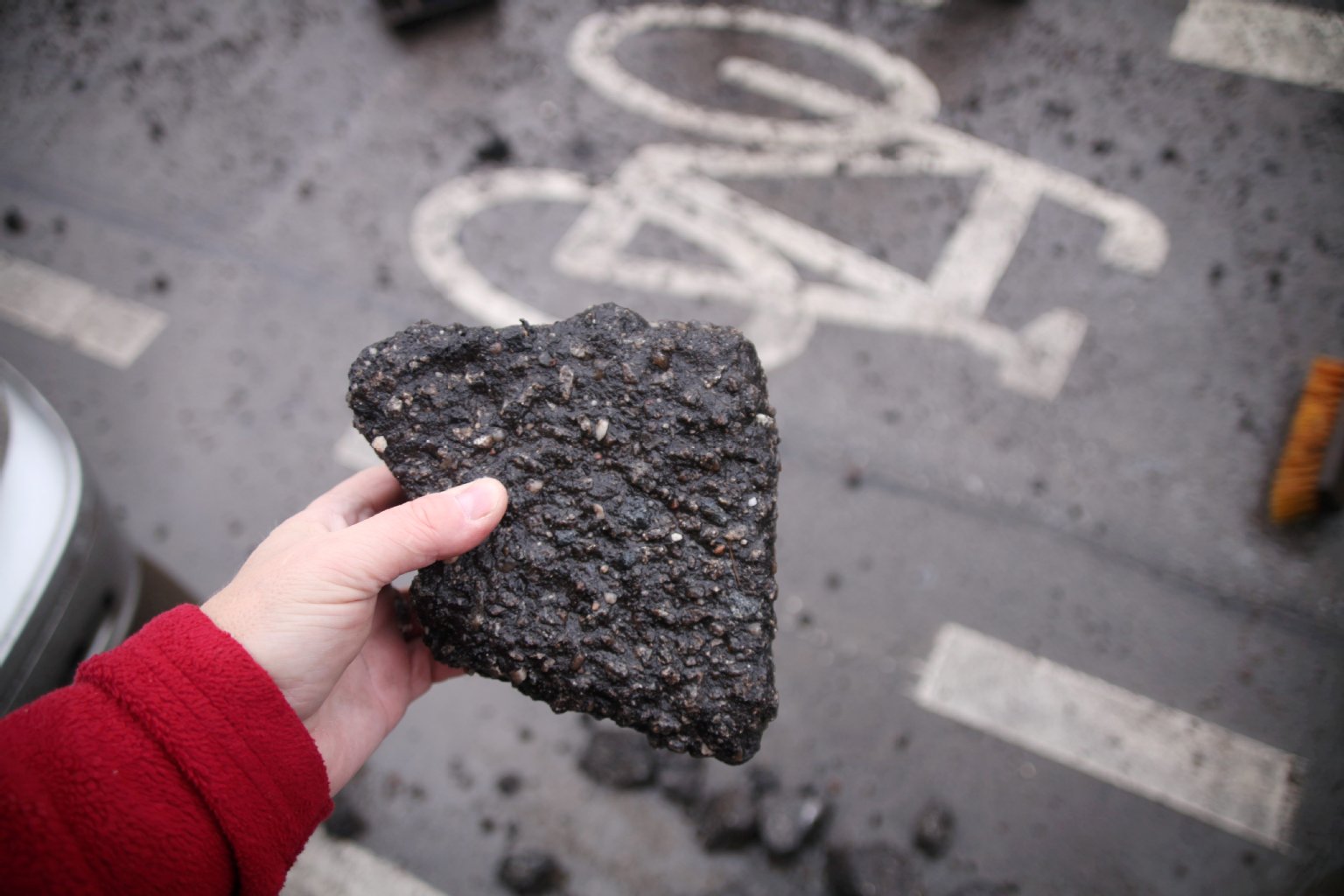 Der KURIER-Reporter hält die Brocken aus dem Schlagloch: Das Stück Asphalt – größer als eine Hand – kann im Verkehr zu einem gefährlichen Geschoss werden.
