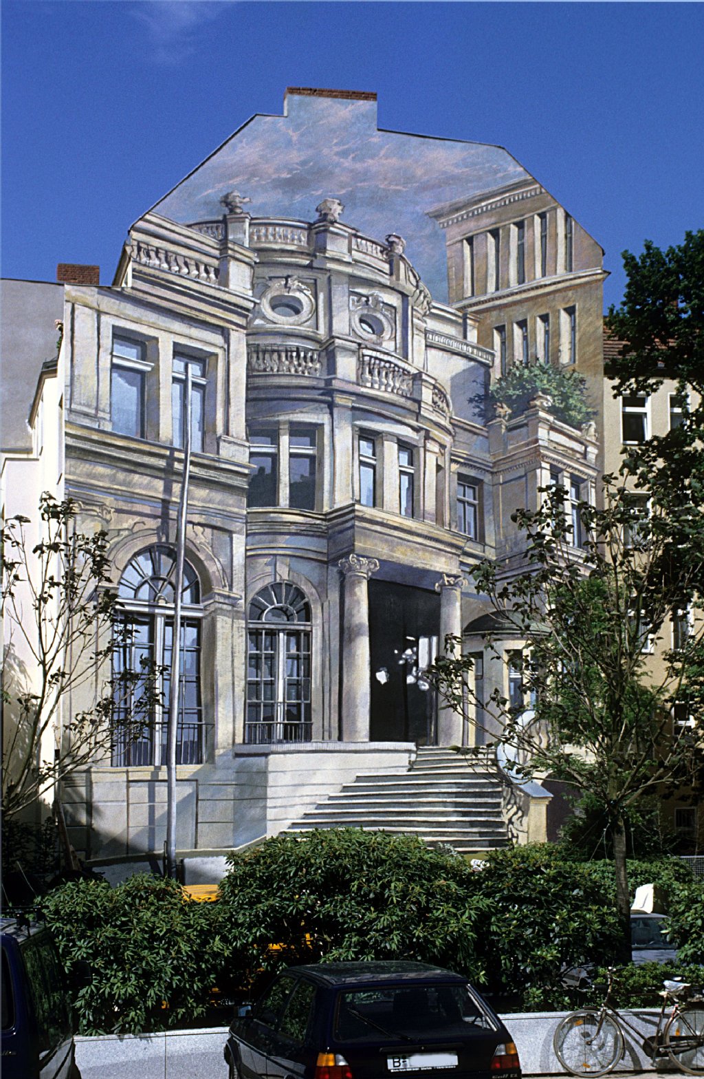 Die Dussmann-Villa (entfernt: 1997): Damals Stasichef Erich Mielkes Gästehaus, heute die Dussmann-Villa (Herzog Villa in Zeuthen). Auftraggeber für das Werk war 1991 die Bayrische Landesbank. Als Dussmann das Haus anschließend kaufte und rauskam, wem das Gebäude ursprünglich gehörte, ließ die Bank das Gemälde (und die Abhörtechnik) 1997 entfernen.