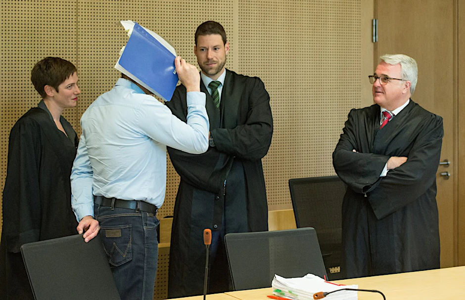 Mario K. verdeckt sein Gesicht beim Gespräch mit zweien seiner drei Anwälte.
