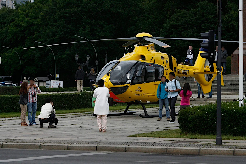 Touristen lassen sich vor dem Hubschrauber ablichten, der vor der Siegessäule gelandet ist. Wenn sie die Retter nicht stören, kann die Polizei nichts tun.