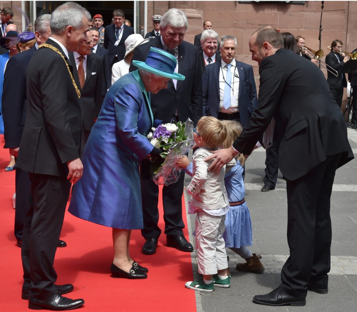 13:30 Uhr: Auf dem Frankfurter Römer (der Rathausvorplatz) nimmt eine gut gelaunte Monarchin einen bunten Blumenstrauß eines sichtlich stolzen Jungen entgegen.